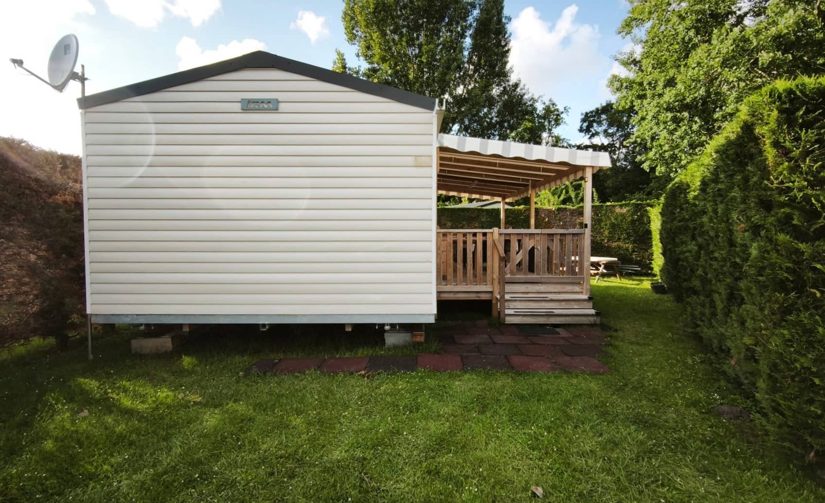 Vue extérieure du mobil-home et de sa grande terrasse sur une parcelle calme