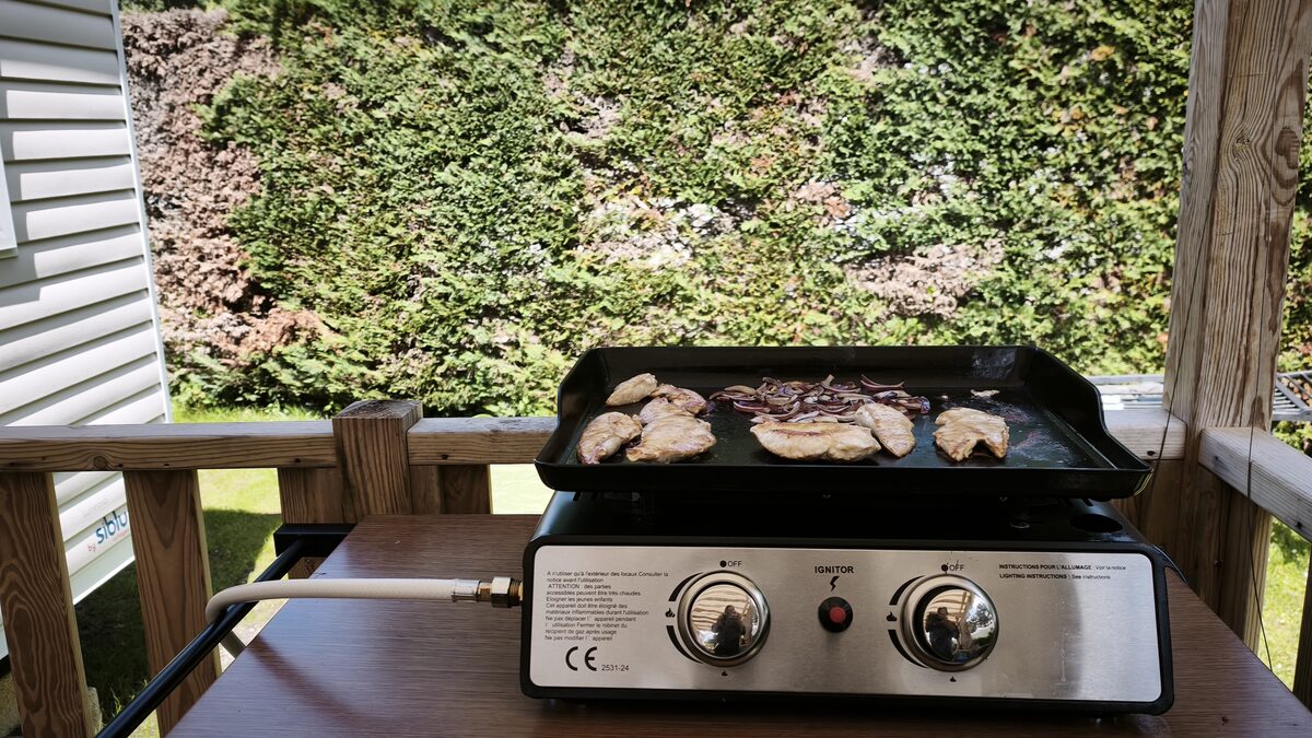 Plancha gaz 2 brûleurs avec poulet et oignons en cuisson